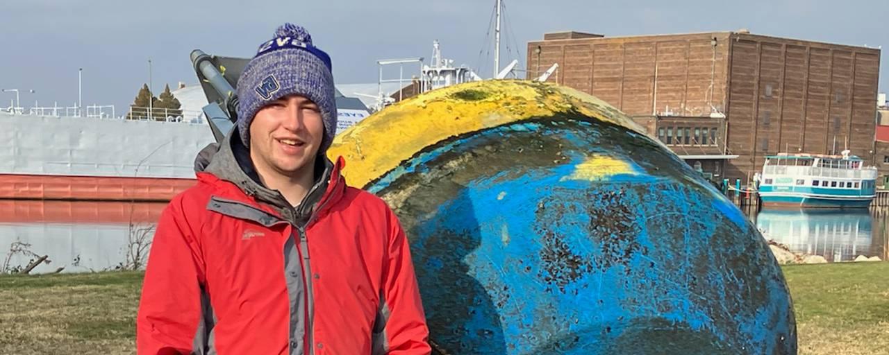 Nate stands next to the 马斯基根 Lake Observatory Buoy